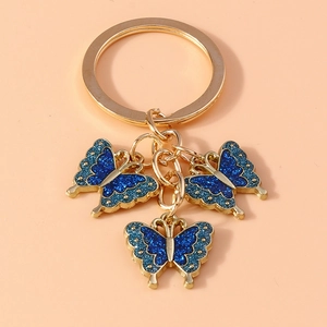 Detailed close-up of three blue glitter butterfly charms on a gold-plated key ring