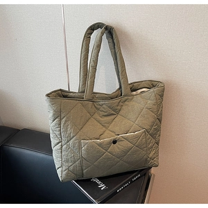 Detail of olive green quilted tote bag with diamond pattern and front snap pocket