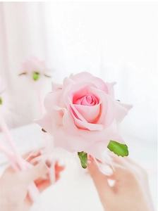 Close-up of a creative pink rose ballpoint pen with realistic fabric petals and green leaves