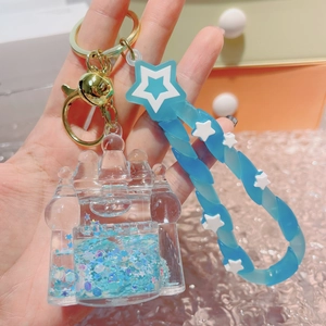 Close-up of blue glowing quicksand castle keychain with gold metal clasp and star strap