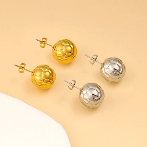 Close-up of gold and silver soccer ball earrings with detailed texture and metallic finish