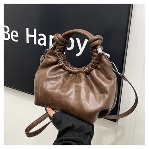 Detail of the brown ruched dumpling bag featuring a unique knotted handle and soft leather