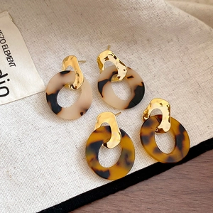 Close-up of leopard print resin hoop earrings with hammered gold metal studs set