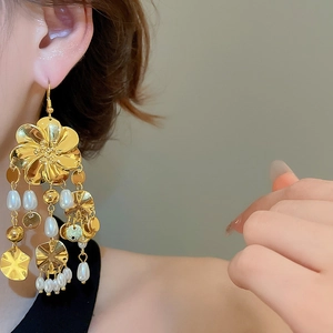 Nahaufnahme von Vintage Gold Blumenohrringen mit weißen Perlenquasten an einem Model