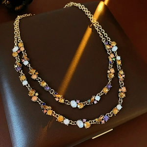 Detailed close-up of double-layer gold necklace with multi-colored gemstones and opal