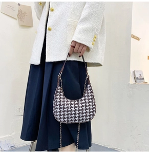 Detailed view of brown and white houndstooth hobo bag with gold chain strap on a model