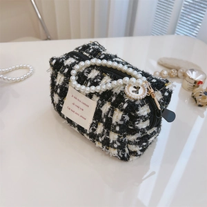 Detail of tweed vanity pouch with elegant pearl handle and gold metallic threads
