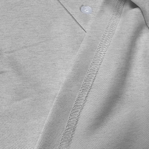 Detailed macro view of gray knitted polo fabric showing fine stitching and a white button
