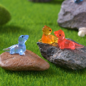 Cute luminous resin lizard figurines on mossy garden landscape, blue orange red colors