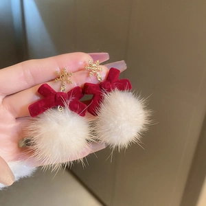 Detail of red velvet bow earrings with white plush ball and gold snowflake charm