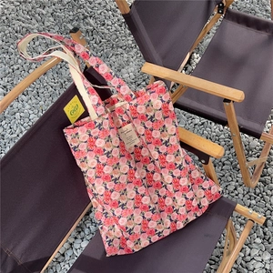 Detailed close-up of pink rose floral print canvas tote bag on an outdoor folding chair