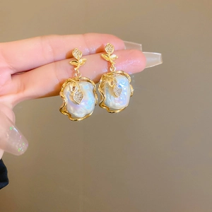 Vue détaillée de boucles d'oreilles feuille dorées avec perles baroques et diamants