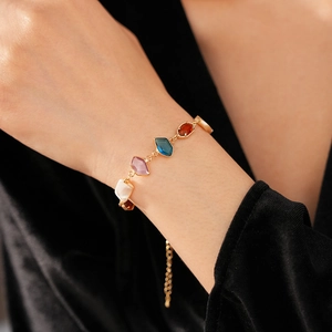 Gros plan d'un bracelet vintage doré avec pierres colorées sur le poignet d'une femme