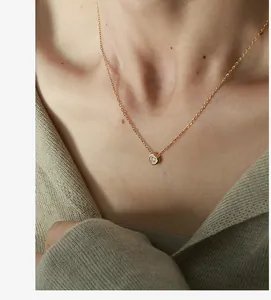 Close-up of a delicate gold hexagon pendant necklace with a zircon on a woman's collarbone