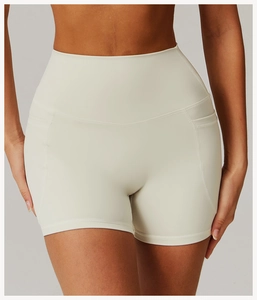 Detail of high waisted cream yoga shorts with functional side pockets and curved stitching