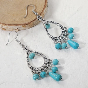 Detailed macro view of vintage bohemian silver teardrop earrings with turquoise blue beads