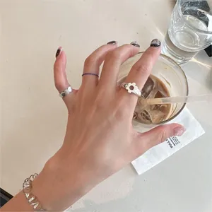 Detail of 925 sterling silver floral ring and chain bracelet on a hand holding coffee