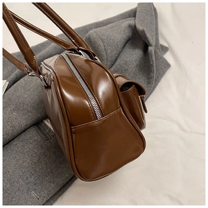 Detailed macro view of dark brown glossy pillow bag with silver zipper and side flap pocket