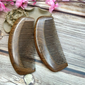 Macro detail of two handcrafted sandalwood hair combs with natural grain on wooden background