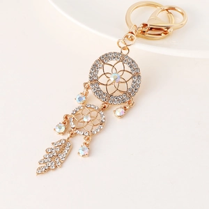 Golden dreamcatcher keychain with sparkling rhinestones and feather pendants on beige background