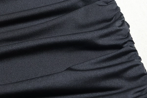 Close-up of ruched black fabric detail with high-elasticity knit texture for slim dress