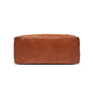 Detailed view of the brown distressed leather texture on the bottom of this tote bag