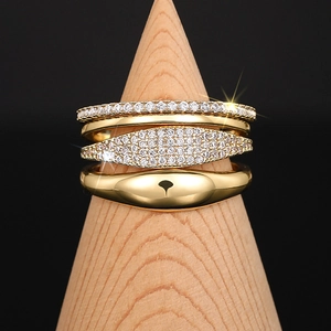 Detail of four stacked gold rings with cubic zirconia inlay on a wooden display stand