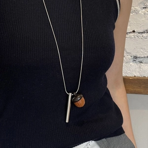 Detail of creative wooden acorn pendant on silver snake chain necklace for women
