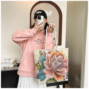 Detail of canvas tote bag featuring vibrant peony floral embroidery and cotton rope handles