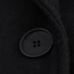 Macro shot of black four-hole button and textured wool fabric on a women long coat