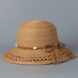 Detailansicht von braunem Raffia-Sonnenhut mit Spitzenkrempe und Perlen-Schleifen-Dekor