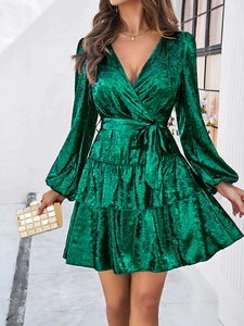 Détail de la robe en velours vert avec col en V, taille lacée et ourlet à volants