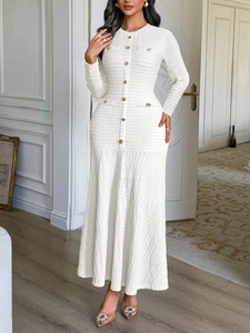 Detail of elegant white tweed dress featuring gold buttons and a refined knit texture