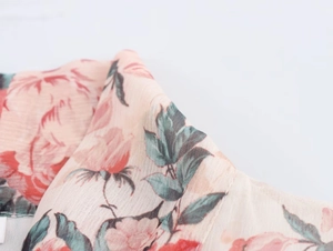 Close-up of lightweight chiffon fabric with delicate pink flowers and green leaf patterns