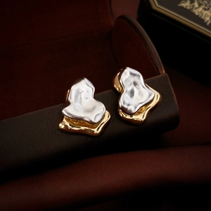Macro shot of gold and silver irregular heart earrings on a premium leather case