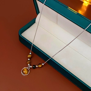 Macro detail of brown tiger eye stone pendant and silver snake chain in a jewelry box