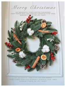 Detail of Christmas wreath with pine needles, red berries, cotton, and cinnamon on white door