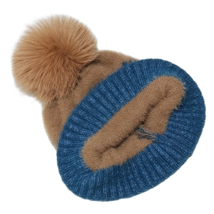 Detail of winter knit beanie featuring blue ribbed cuff and brown faux fur pom-pom