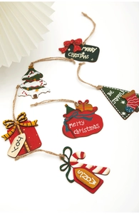 Close-up of 6 painted wooden Christmas tree ornaments with festive tags and rustic jute ropes