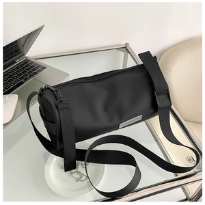 Détail d'un sac cylindrique noir sur une table avec accessoires de style de vie moderne