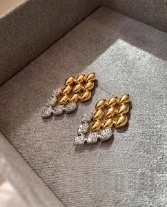 Détail des boucles d'oreilles losanges bicolores avec zircons pavés dans un écrin
