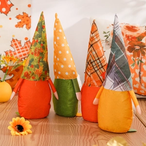Set of four autumn harvest faceless gnomes with maple leaf decor on wooden surface