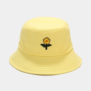 Dettaglio ravvicinato del cappello a secchiello giallo con ricamo floreale e cuciture rinforzate