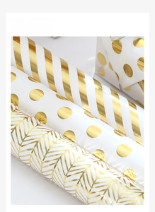 Detail view of white gift wrapping paper with metallic gold stripes and polka dots