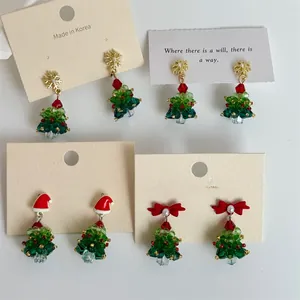 Detail of handmade beaded Christmas tree earrings with crystals and festive red bows