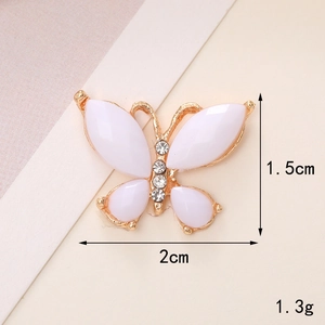 Macro shot of a butterfly charm showing dimensions 2cm by 1.5cm with rhinestone details