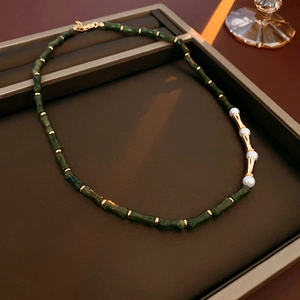 Dettaglio ravvicinato della collana vintage stile bambù con perle verdi e oro elegante