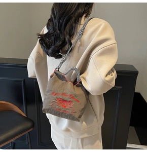 Detailed view of the nylon shoulder bag with butterfly embroidery on model's back
