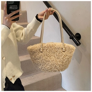 Détail du sac à main beige en polaire bouclée avec anses en cuir sur un escalier