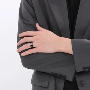 Close-up of a wide black stainless steel ring on a male hand with silver shell details